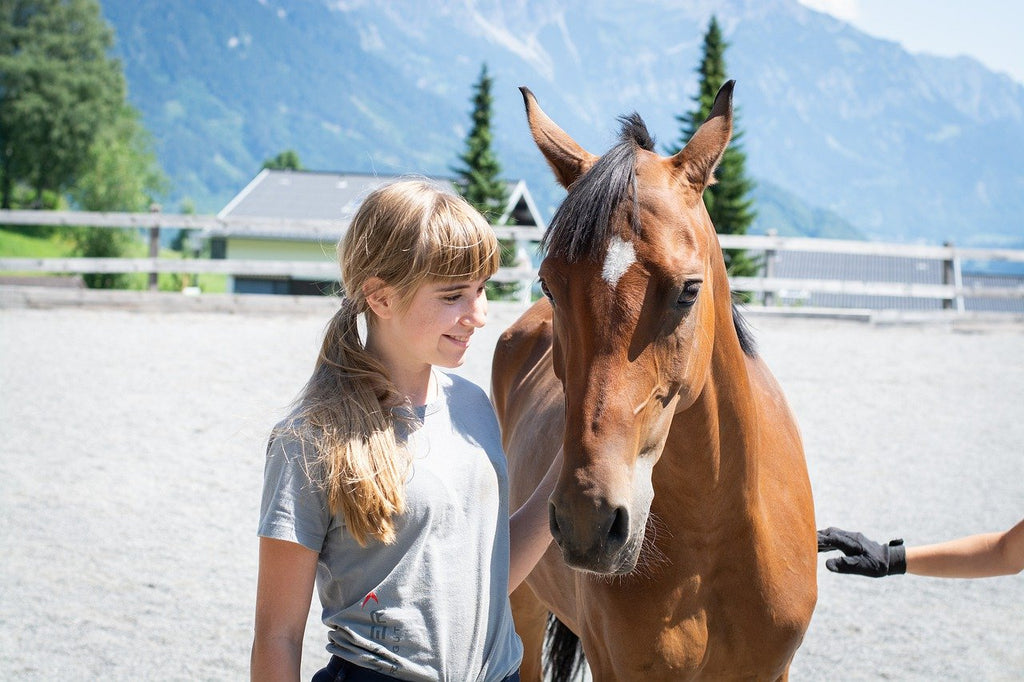 Jeune fille souriante à côté d'un cheval, dans une carrière